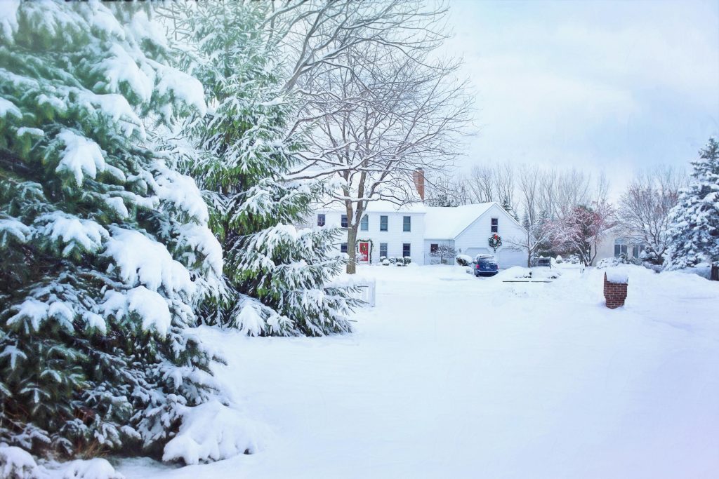 Massachusetts home exterior in winter with snow, gutters cleared and lights on inside—prepared for seasonal home maintenance.”